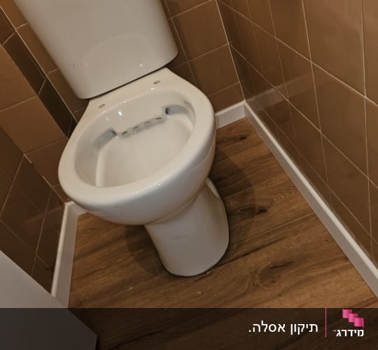 אסלה בחדר שירותים עם רצפת עץ
